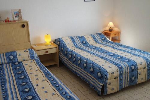 une chambre d'hôtel avec 2 lits, une table et des lampes dans l'établissement Face à la mer appartement T2 dans résidence avec parking - 5SOL16, à Saint Cyprien Plage
