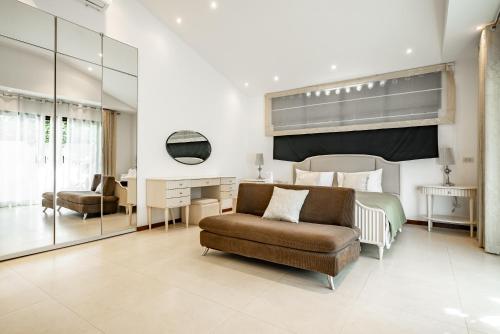 Un dormitorio con una cama, un sofá y una silla. en Villa Andre by VillaCarte, en Nai Harn Beach