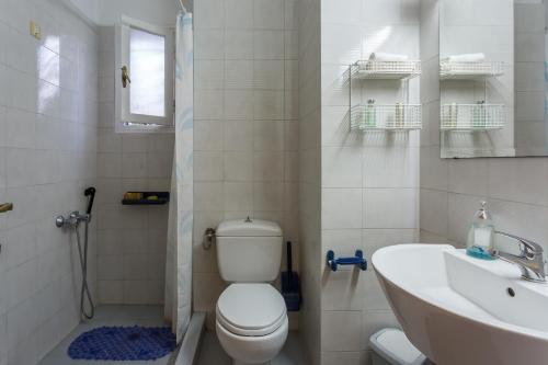 a white bathroom with a toilet and a sink at Eleni's town apartment in Skopelos Town