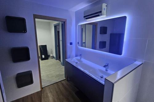 une salle de bain bleue avec un lavabo et un miroir dans l'établissement Le Pavillon dans le Parc, à Saulxures-sur-Moselotte