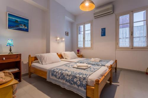 two beds in a room with two windows at Eleni's town apartment in Skopelos Town