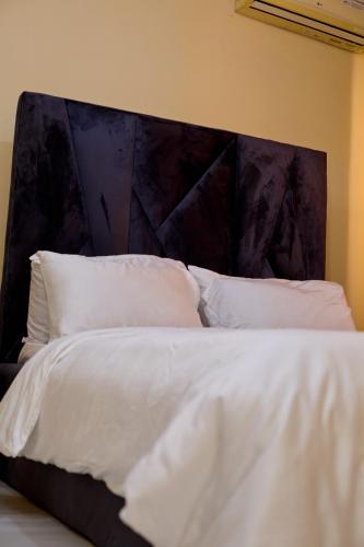 a white bed with a large headboard with white pillows at Builders Homes and Apartments in Ibadan