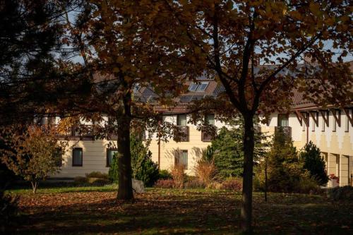 a white house with trees in front of it at Hotel & Restauracja Timberland in Orzesze