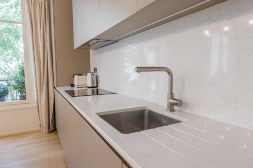 une cuisine blanche avec un évier et une fenêtre dans l'établissement Chic apartment - 2BR-4P - Trocadero, à Paris