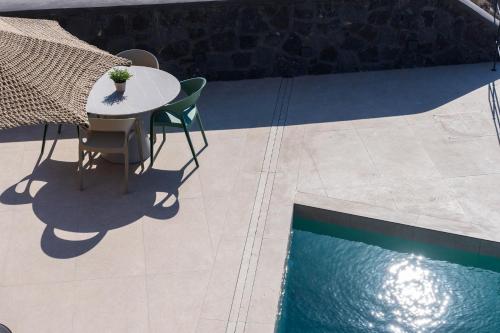 a table and chairs next to a swimming pool at Bay View Residences Santorini in Akrotiri