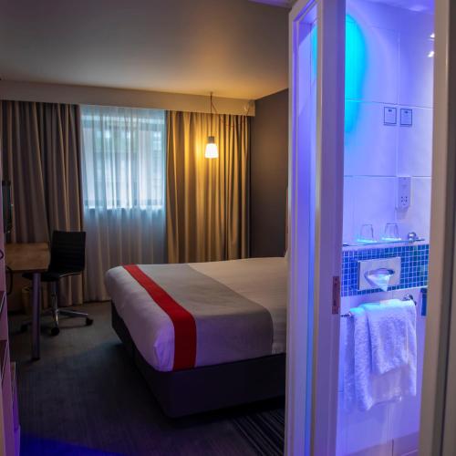 a hotel room with a bed and a table with a chair at Holiday Inn Express Royal Docks by IHG in London