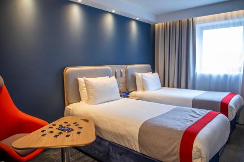 a hotel room with two beds and a chair at Holiday Inn Express Royal Docks by IHG in London