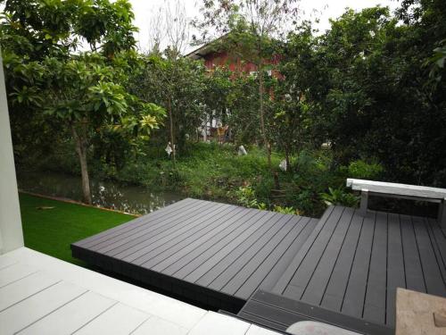 a wooden deck with a bench and a garden at Lamp U House Amphawa in Amphawa
