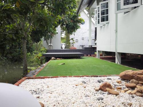 a backyard with a green lawn and a house at Lamp U House Amphawa in Amphawa