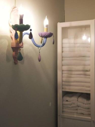 a bathroom with a light on the wall with towels at Lamp U House Amphawa in Amphawa