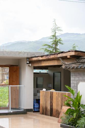 a house with a balcony with mountains in the background at Shan Di B&B in Lijiang