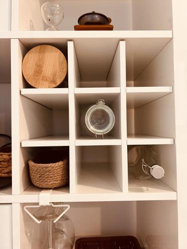 a white pantry with shelves with bowls and plates at ONE Guest Place Master Bedroom near the Beach in Abu Dhabi