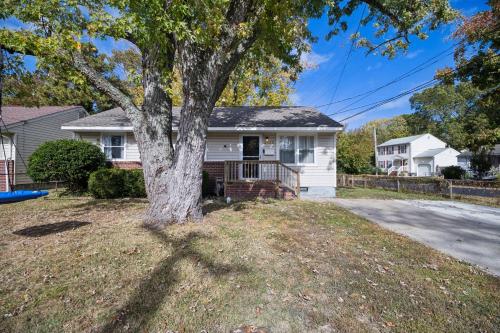 a white house with a tree in the yard at Comfy Coastal Getaway with Modern Comforts home in Hampton