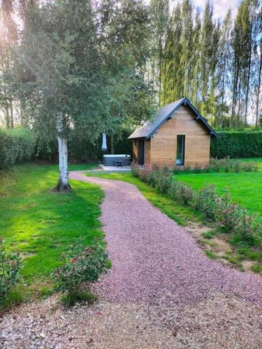 a small wooden cabin in a field with a tree at ptit cocon in Le Fournet