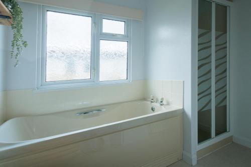 a white bathroom with a tub and a window at Peaceful Riverside Family Retreat in Christchurch
