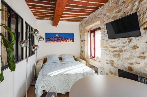 - une chambre avec un lit et une télévision sur un mur en pierre dans l'établissement L'Agora - Proche Pharo, Vieux port, Saint-Victor Noailles, à Marseille