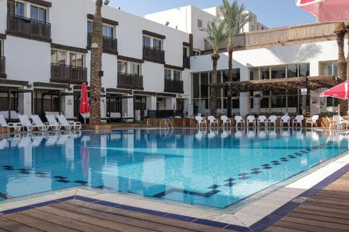 a large swimming pool with chairs and a building at G hotel in Eilat