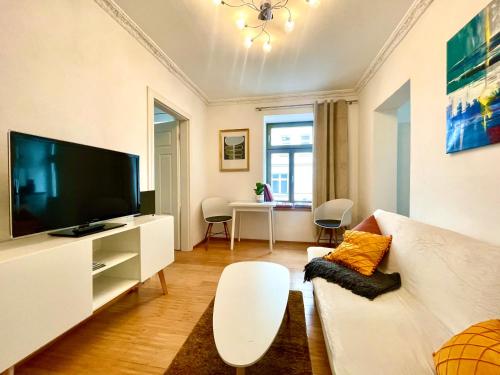 a living room with a white couch and a flat screen tv at Gästeapartment Leipzig City in Leipzig
