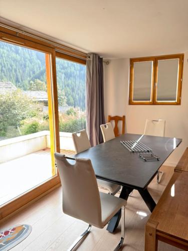 une table de salle à manger avec des chaises et une grande fenêtre dans l'établissement Le CarrozBlanc, à Peisey-Nancroix