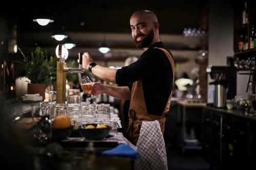 a man in a kitchen preparing a drink at Sky Hotel Apartments, Stockholm in Stockholm