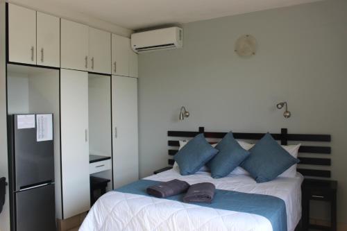 a bedroom with a bed with blue pillows and a refrigerator at ATKV Natalia in Kingsburgh