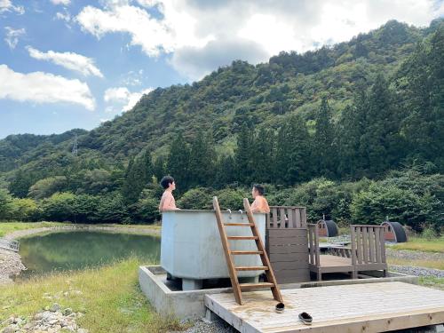 two people standing in a bath tub near a body of water at Cozmo in Nikko