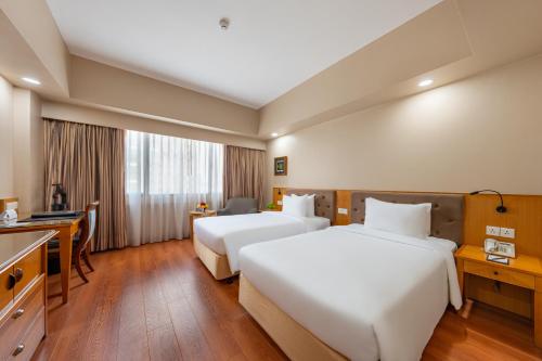 a hotel room with two beds and a desk at Saigon Prince Hotel in Ho Chi Minh City