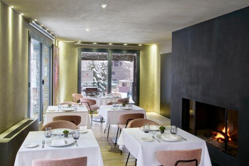 a restaurant with tables and chairs and a fireplace at NH Collection Andorra Palomé in La Massana
