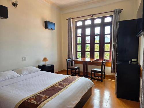 a bedroom with a bed and a desk and a window at Villa Pink House in Da Lat