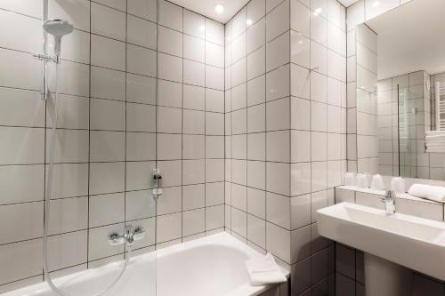 a white bathroom with a tub and a sink at Libertel Gare Du Nord Suede in Paris