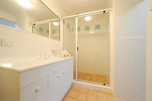a white bathroom with a shower and a sink at at Beach Court Holiday Villas in Airlie Beach