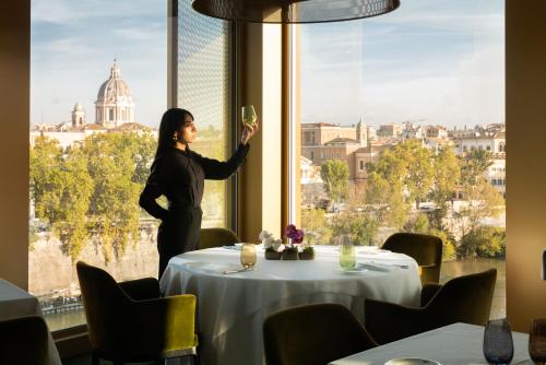 a woman standing at a table with a glass of wine at The First Musica - Preferred Hotels & Resorts in Rome