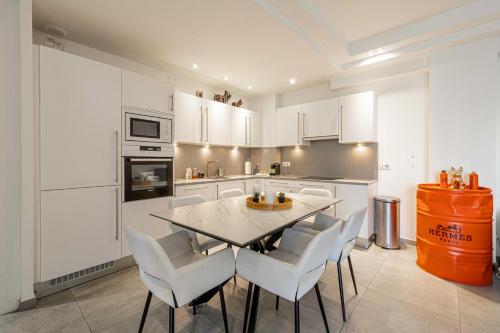 une cuisine avec des armoires blanches et une table et des chaises dans l'établissement Modern 1 bedrm apt with balcony - Cannes-Croisette, à Cannes