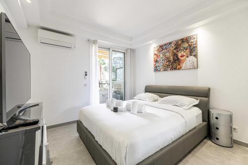 une chambre blanche avec un grand lit et une télévision dans l'établissement Modern 1 bedrm apt with balcony - Cannes-Croisette, à Cannes