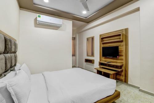 a white bedroom with a bed and a tv at Hotel O Maple view in Naroda