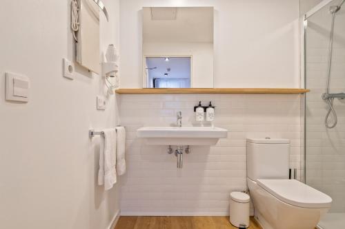 a white bathroom with a sink and a toilet at Uma Suites Ondarreta in Donostia-San Sebastián