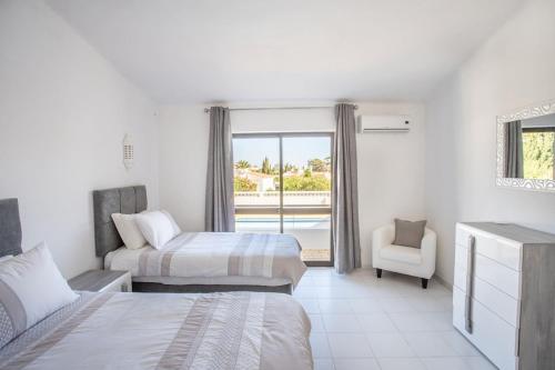 a bedroom with two beds and a chair and a window at Carosim - Quiet location, close to beach, private in Poço Partido