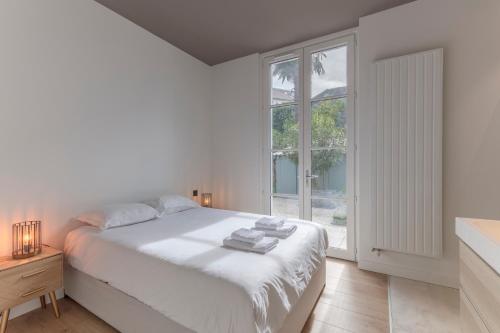 une chambre blanche avec un lit et une fenêtre dans l'établissement Superbe Maison avec Jardin - La Villa Paloise, à Pau