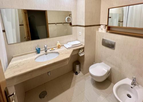 a bathroom with a sink and a toilet and a mirror at Carvoeiro terrace - Stay in the heart of Carvoeiro in Carvoeiro