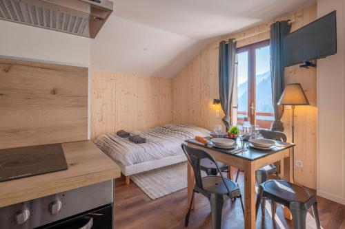 une pièce avec une table, des chaises et un lit dans l'établissement Le Petit Aravis - village et vue panoramique, à La Giettaz