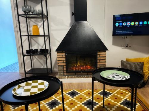 two tables in a living room with a fireplace at Ático gran terraza cerca BCN in Castelldefels