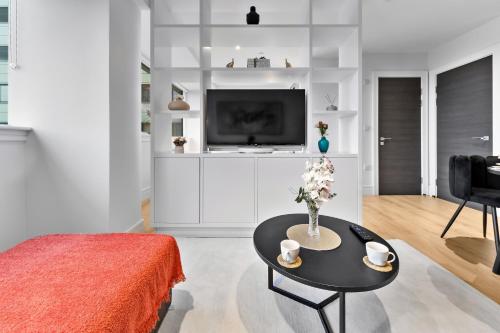 a living room with a table and a tv at Stylish Retreats on Olympic Way in London