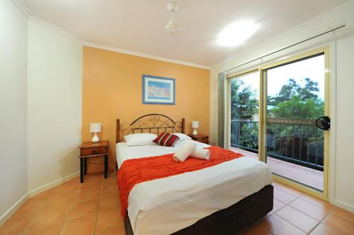 a bedroom with a bed and a large window at at Beach Court Holiday Villas in Airlie Beach