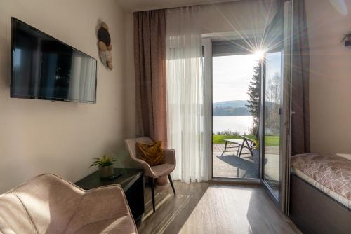 a living room with a bed and a sliding glass door at Rezidence Sunny Hill in Frymburk