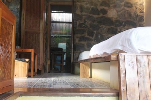 a bedroom with a bed and a stone wall at Ha Giang Ecolodge in Ha Giang