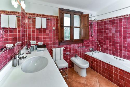 La salle de bains est pourvue de carrelage rouge, d'un lavabo et de toilettes. dans l'établissement Suite Mestral im Es Llobets, à Llucmajor
