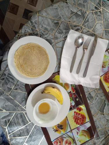 a table with two plates of food and a banana at Sunshine homestay in Tānsing