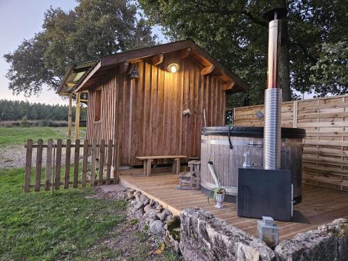 Ce chalet en bois dispose d'une terrasse en bois avec un poêle. dans l'établissement Roulotte Belle des Prés, à Sigalens