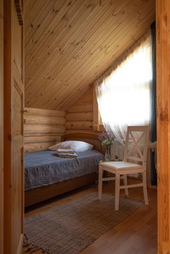 a bedroom with a bed and a chair in a room at Kurna Mõisa Saunaküla in Kurna