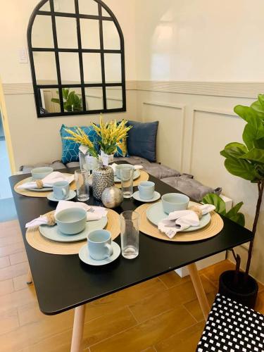 a black table with plates and cups and dishes on it at Seawind Condominium Near Airport in Davao City